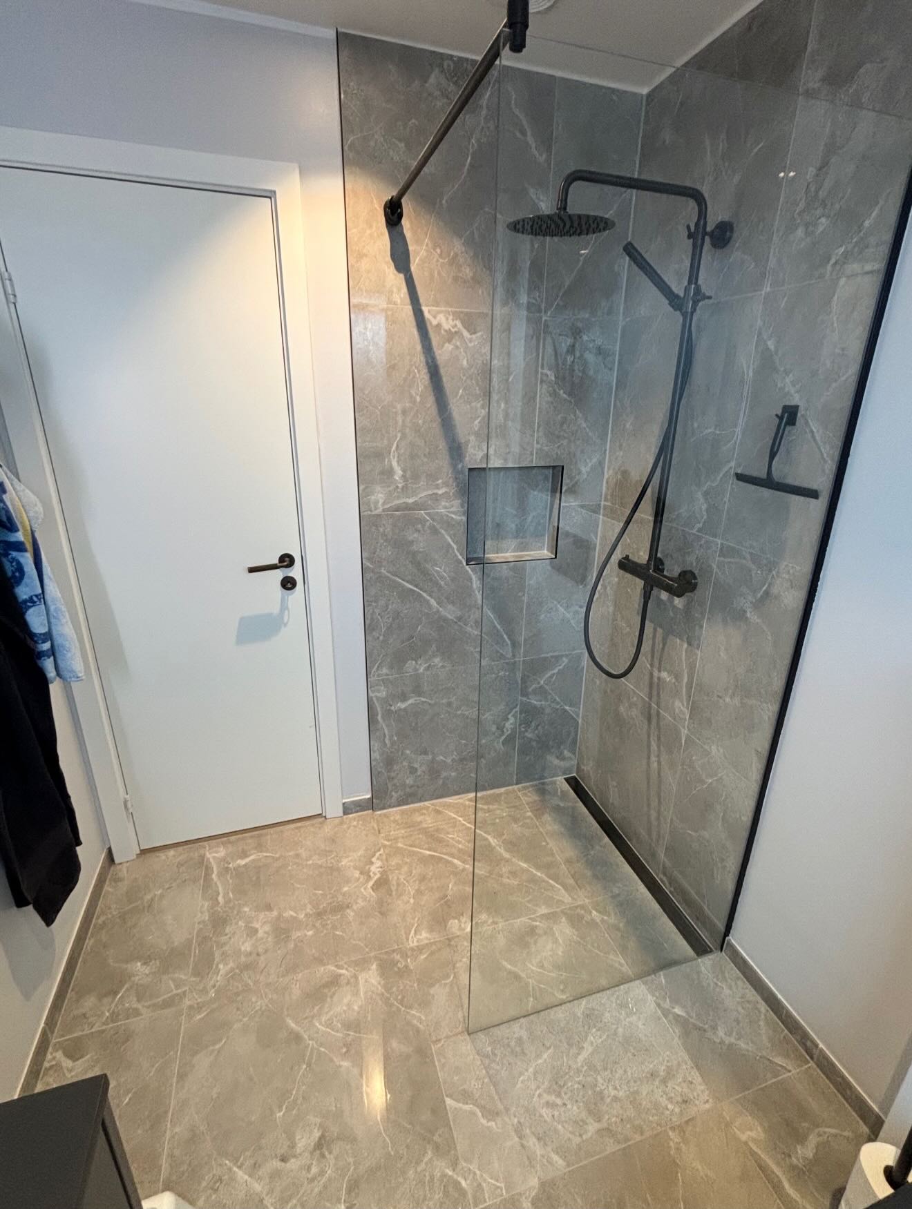 Sort toilet og gulv i grå marmorlook-fliser